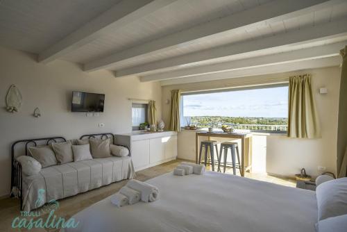 a living room with a white couch and a kitchen at Trulli Casalina in Cisternino