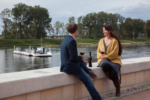 Ein Mann und eine Frau sitzen an einer Wand neben einem Fluss in der Unterkunft Hotel & Restaurant Gasthaus Zum Anker in Elster