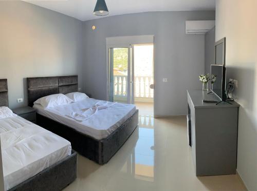 ein Schlafzimmer mit zwei Betten und einem Schreibtisch und einem Fenster in der Unterkunft Vila Chelsea in Ksamil
