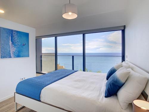 a bedroom with a large bed with a large window at Villa Calhau by LovelyStay in Ponta do Sol
