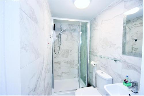 a bathroom with a shower and a toilet and a sink at The Aldgate Rooms in London