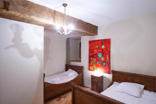 a bedroom with two beds and a painting on the wall at Gîte La Terrasse - Manoir le Plessix Madeuc in Corseul