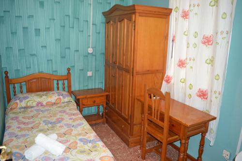 a bedroom with a bed and a wooden cabinet and a table at Hostal Doña Carmen in Ronda