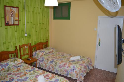 two beds in a room with green walls at Hostal Doña Carmen in Ronda