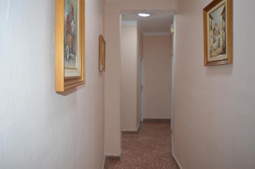 a hallway with two pictures on the wall and a door at Hostal Doña Carmen in Ronda