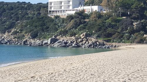 una spiaggia sabbiosa con un grande edificio sullo sfondo di B&B is pranus a mari casa privata a Solanas