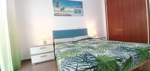 Schlafzimmer mit einem Bett mit einer grünen und weißen Bettdecke in der Unterkunft Fantástico apartamento al lado del Serrallo in Tarragona