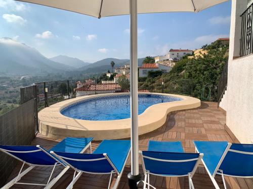 a pool with chairs and an umbrella on a deck at Villa Montesolana in Pedreguer