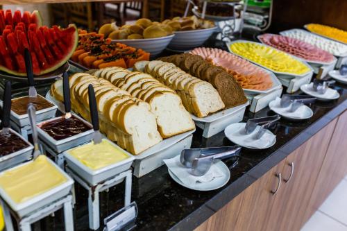 a buffet filled with different types of bread and fruit at HsHotelaria - Filial Bombinhas in Bombinhas