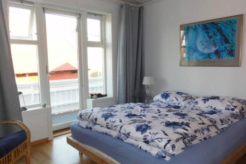 a bedroom with a bed with a blue and white blanket at Charming flat in cosy farmhouse in Skudeneshavn