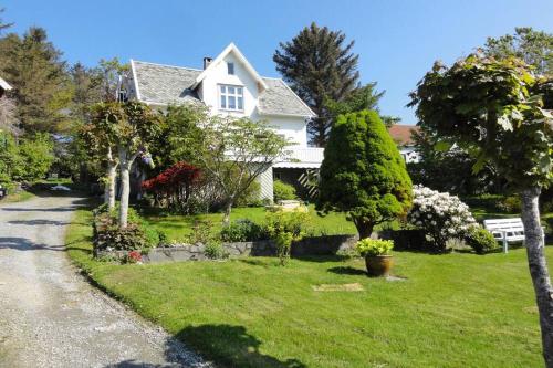 a white house with trees and flowers in the yard at Charming flat in cosy farmhouse in Skudeneshavn