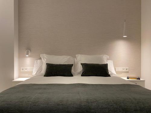 a bedroom with a large white bed with black pillows at HNN GRANADA in Granada