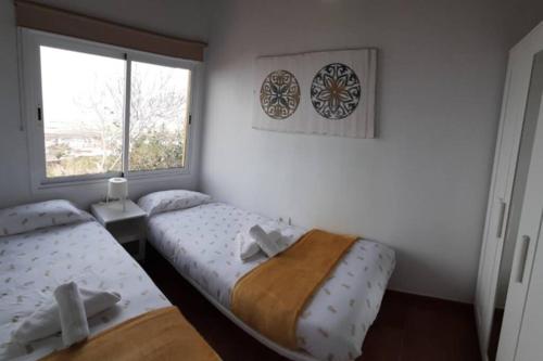 1 dormitorio con 2 camas y ventana en Casita con Encanto en Frontera