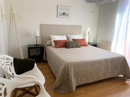 a bedroom with a large bed and a white chair at Aticos La Aliseda by Valdesierra in Béjar