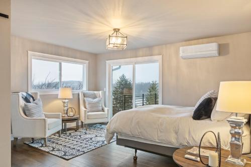 a bedroom with a bed and two chairs and a window at Lakeview Luxury in Hope