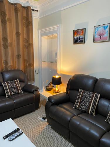 a living room with a leather couch and a chair at Loch Lomond Apartments in Dumbarton
