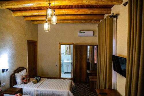 a bedroom with a bed and a television in a room at Old Gate Hotel in Bukhara