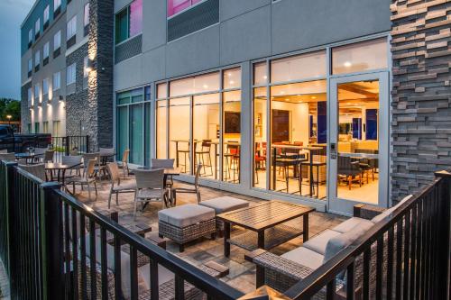 a balcony with tables and chairs on a building at Holiday Inn Express & Suites - Denton South by IHG in Denton