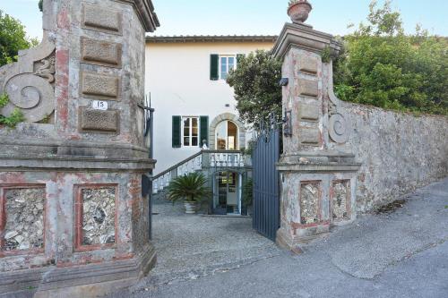 una vecchia casa con un cancello e un muro di Villa Le Cipresse a San Quirico di Moriano