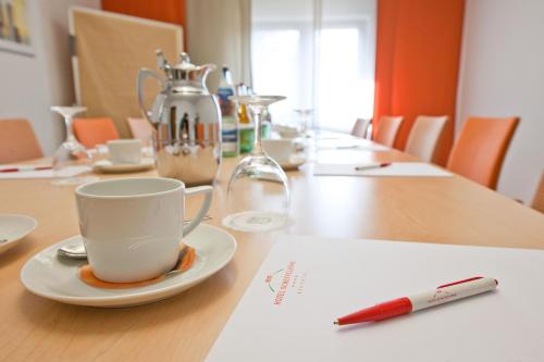 a cup of coffee on a table with a pen at Hotel Scheffelhöhe in Bruchsal