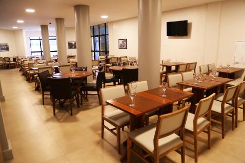 Real Praia Hotel في أراكاجو: غرفة طعام مع طاولات وكراسي خشبية