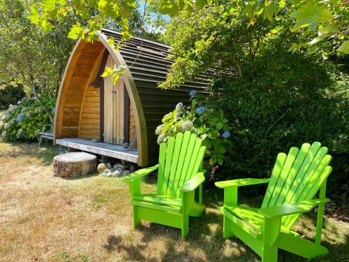 two green chairs sitting in front of a cabin at Tui Ridge Eco Cabins in Aongatete