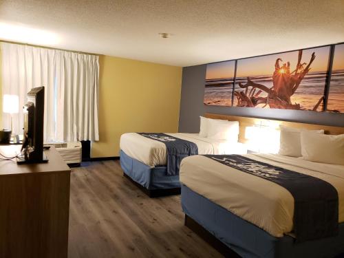 a hotel room with two beds and a painting on the wall at Days Inn & Suites by Wyndham Merrillville in Merrillville