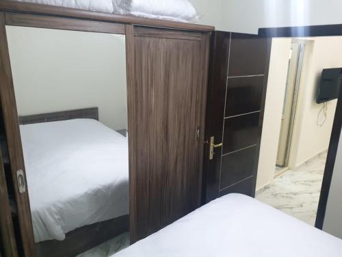 1 dormitorio con 2 camas y armario de madera en Bravey Apartments, en Hurghada