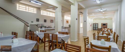 a dining room with white tables and wooden chairs at Colonial Hotel Itatiba in Itatiba