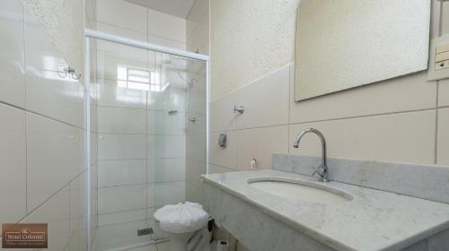 a bathroom with a sink and a shower with a mirror at Colonial Hotel Itatiba in Itatiba