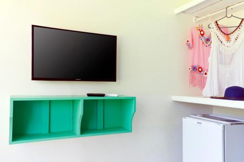 a living room with a green table and a tv at Pousada Terceiro Espaço in Guaibim