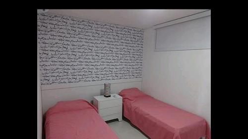 um quarto com 2 camas com lençóis vermelhos e uma parede em CARNEIROS BEACH RESORT- Flat de 2 quartos - condomínio à beira mar da Praia de Carneiros em Praia dos Carneiros