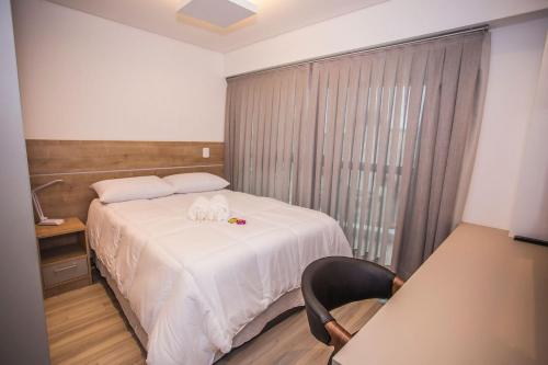 a bedroom with a bed and a chair and a window at Apartamento 1 Quarto no Seventh Avenue - SEV1206 in Curitiba
