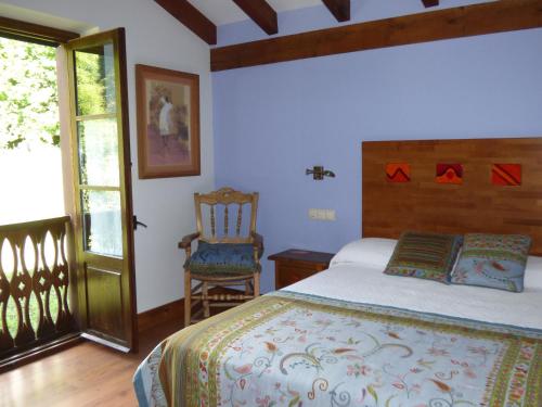 a bedroom with a bed and a chair and a window at Casa Rural Los Riegos in Caso
