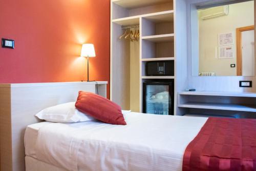 a bedroom with a white bed with a red pillow at Hotel Accademia in Bologna