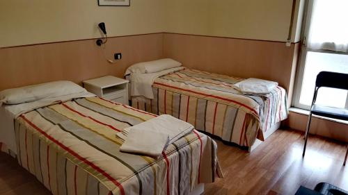 a hotel room with two beds and a window at Affittacamere Metro Fiera in Pero