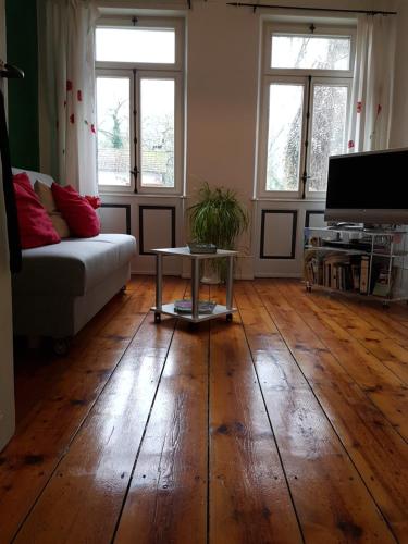 a living room with a couch and a table on a wooden floor at Zwischen-Rhein-und-Reben, zentral, barrierefrei in Speyer