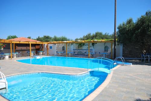 een groot zwembad met blauw water in een tuin bij Hotel Marina Village in Palekastron
