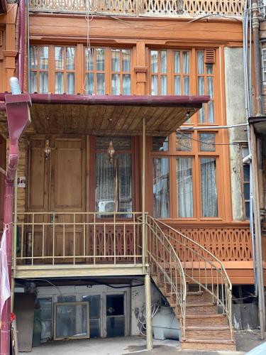a wooden building with a staircase in front of it at Boutique Fantasy in Tbilisi City