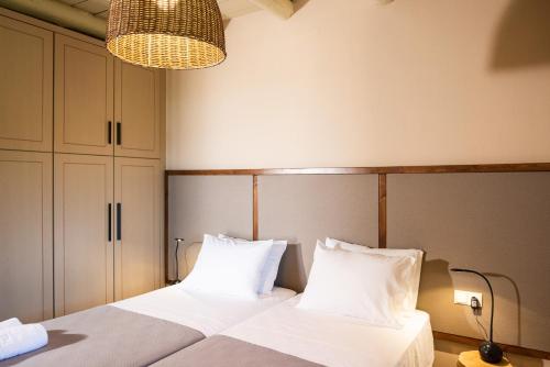 a bedroom with a bed with white sheets and a chandelier at Prinus Country Retreat Apokoronas, heated pool, 13km from the sea in Embrósneros