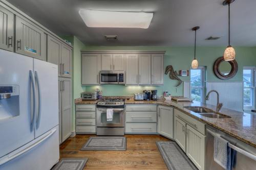 een keuken met witte apparatuur, groene muren en houten vloeren bij Folly 'B' Golly in Folly Beach