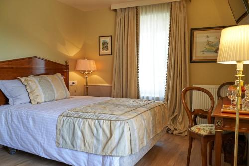 a bedroom with a bed and a desk and a window at HOTEL Les Contes de Bruyeres in Servières-le-Château