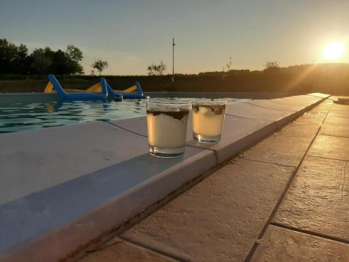 two glasses of beer sitting on the edge of a swimming pool at Relais Villa Sofia in Calcinelli