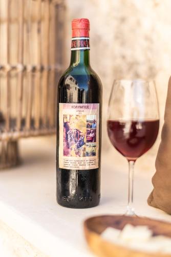 a bottle of red wine next to a glass at Prinus Country Retreat Apokoronas, heated pool, 13km from the sea in Embrósneros
