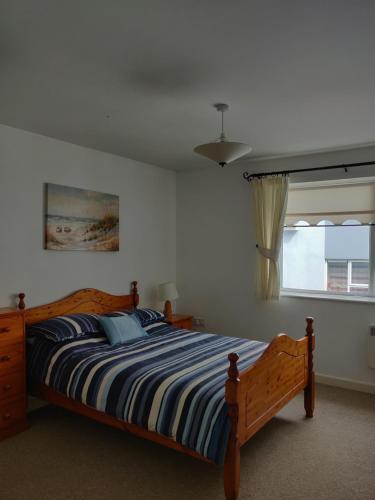 a bedroom with a bed with a blue and white striped blanket at Riverview Apartment in Skibbereen