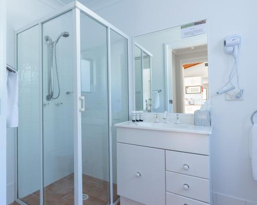a white bathroom with a shower and a sink at Hunter Gleann Pty Ltd in Pokolbin