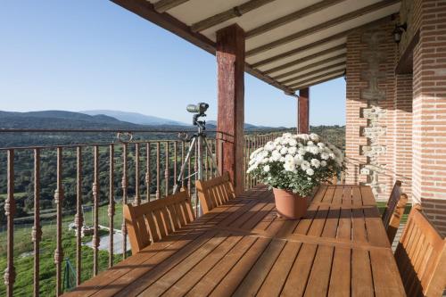 un porche con dos bancos y una maceta de flores en Casa Rural & SPA Mirador de la Covatilla en Guijo de Ávila