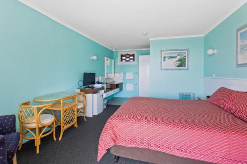 a bedroom with a bed and a table and a desk at Swansea Motor Inn Tasmania in Swansea