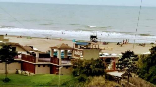 una casa junto a una playa con gente en ella en Vista Al Mar en San Clemente del Tuyú