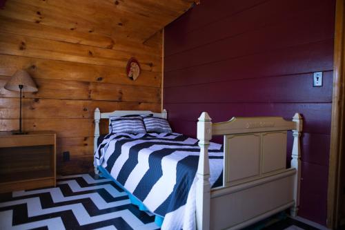 a bedroom with a bed and a wooden wall at Hicksville Pines Chalets & Motel in Idyllwild